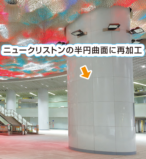 結晶化ガラス壁材・床材(人工大理石調ガラス)のニュークリストンの内装材で湾曲加工パネルをエレベーター前の大きな柱に施工している写真