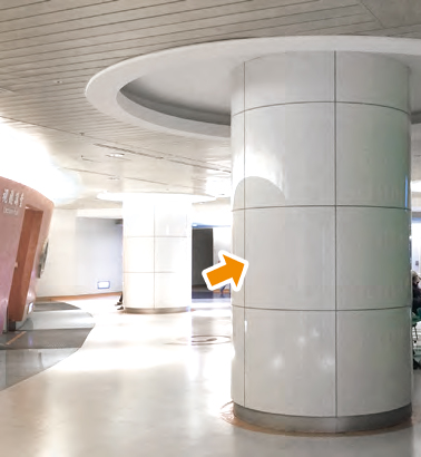 ニュークリストン（人工大理石調ガラス材）の内装材で湾曲加工パネルを待合室ホールの円柱部分に施工している写真